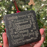 Load image into Gallery viewer, A slate coaster with various words engraved on it, held in a hand with a Christmas tree in the background.