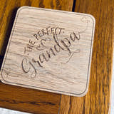 Load image into Gallery viewer, A wooden coaster with 'The Perfect Grandpa' text laser engraved on it, placed on a wooden surface.