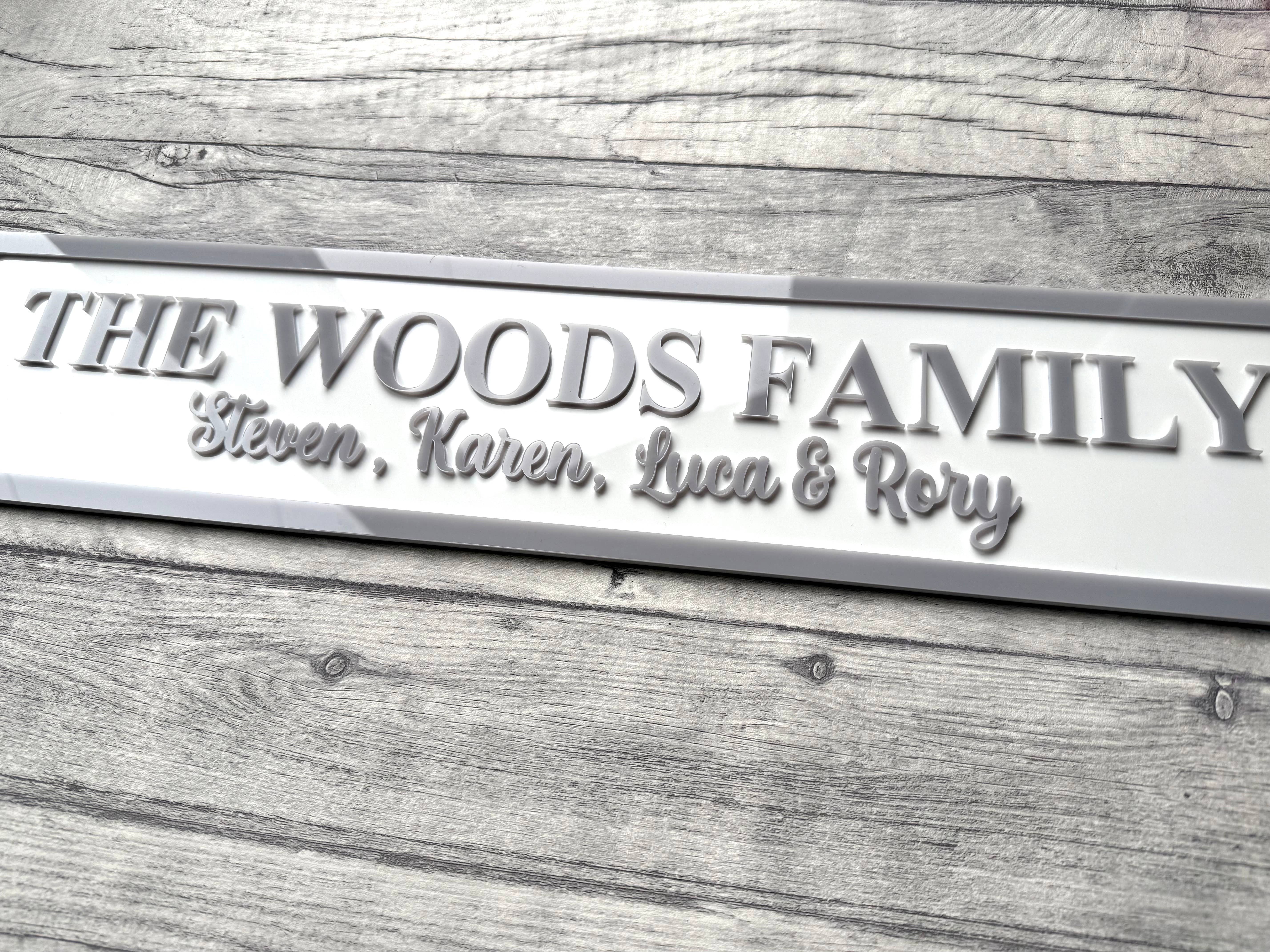 Family nameplate with 'The Woods Family' and names engraved on a wooden surface