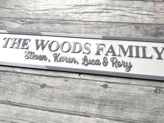 Family nameplate with 'The Woods Family' and names engraved on a wooden surface
