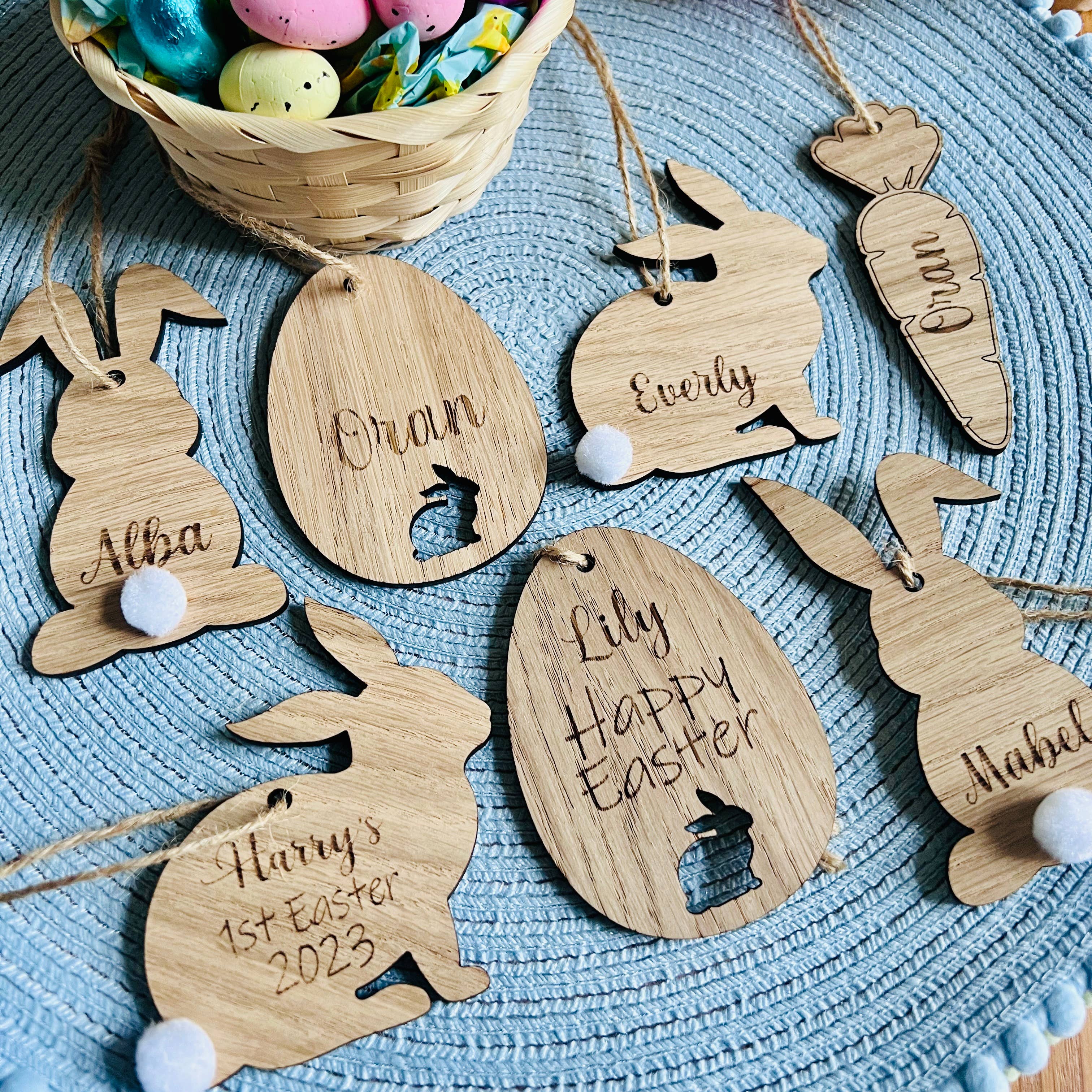 A set of seven wooden hanging Easter decorations, including bunny shapes and an egg design, with personalized engravings of names.