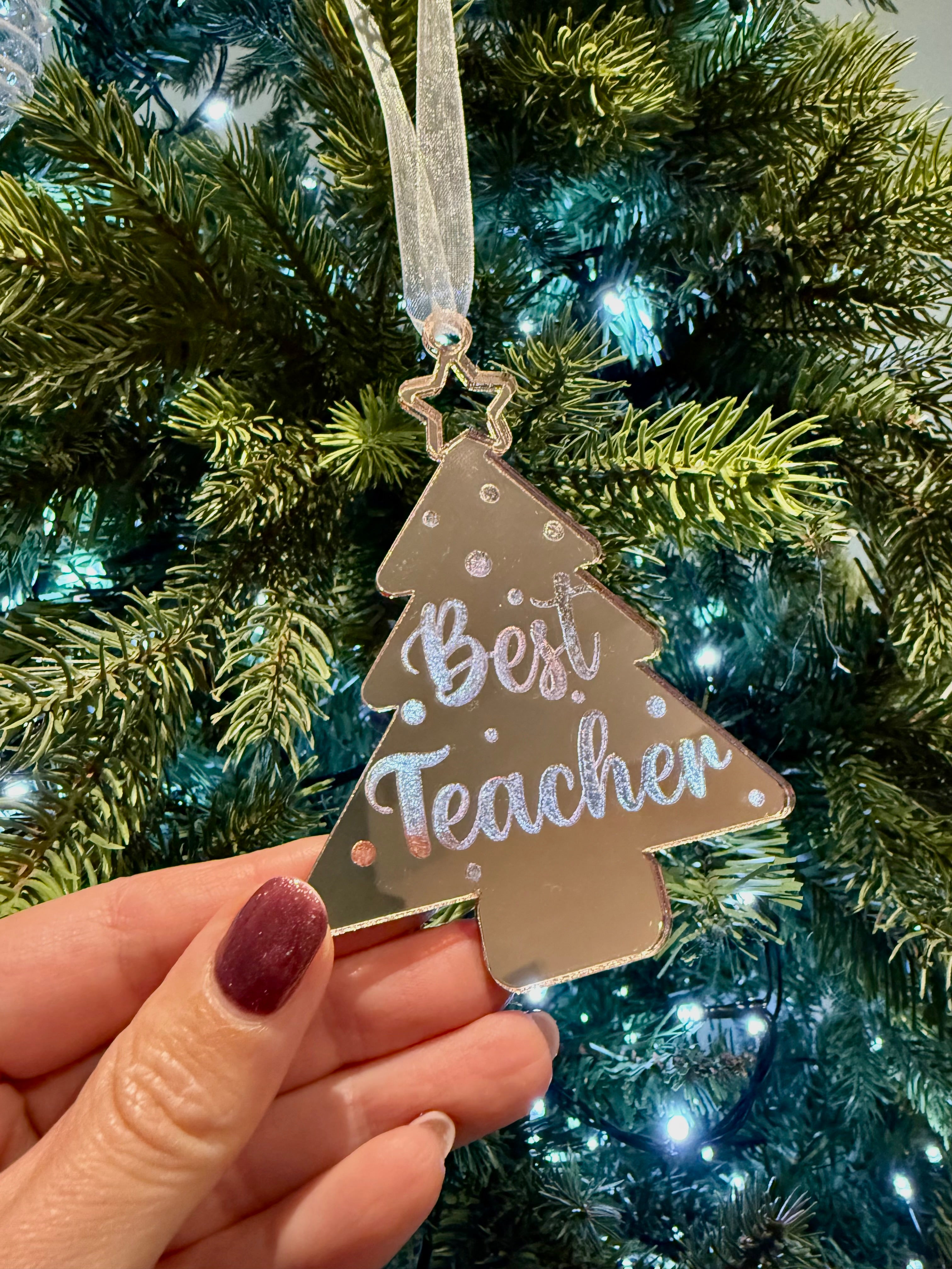 Load image into Gallery viewer, Decorative ornament with 'Best Teacher' text held in front of a Christmas tree.
