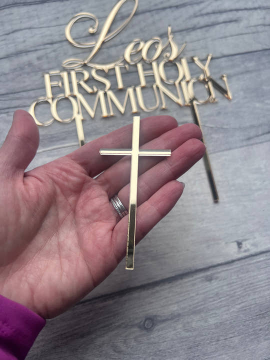 Gold cross and 'Forever Communion' decorative items on a wooden surface