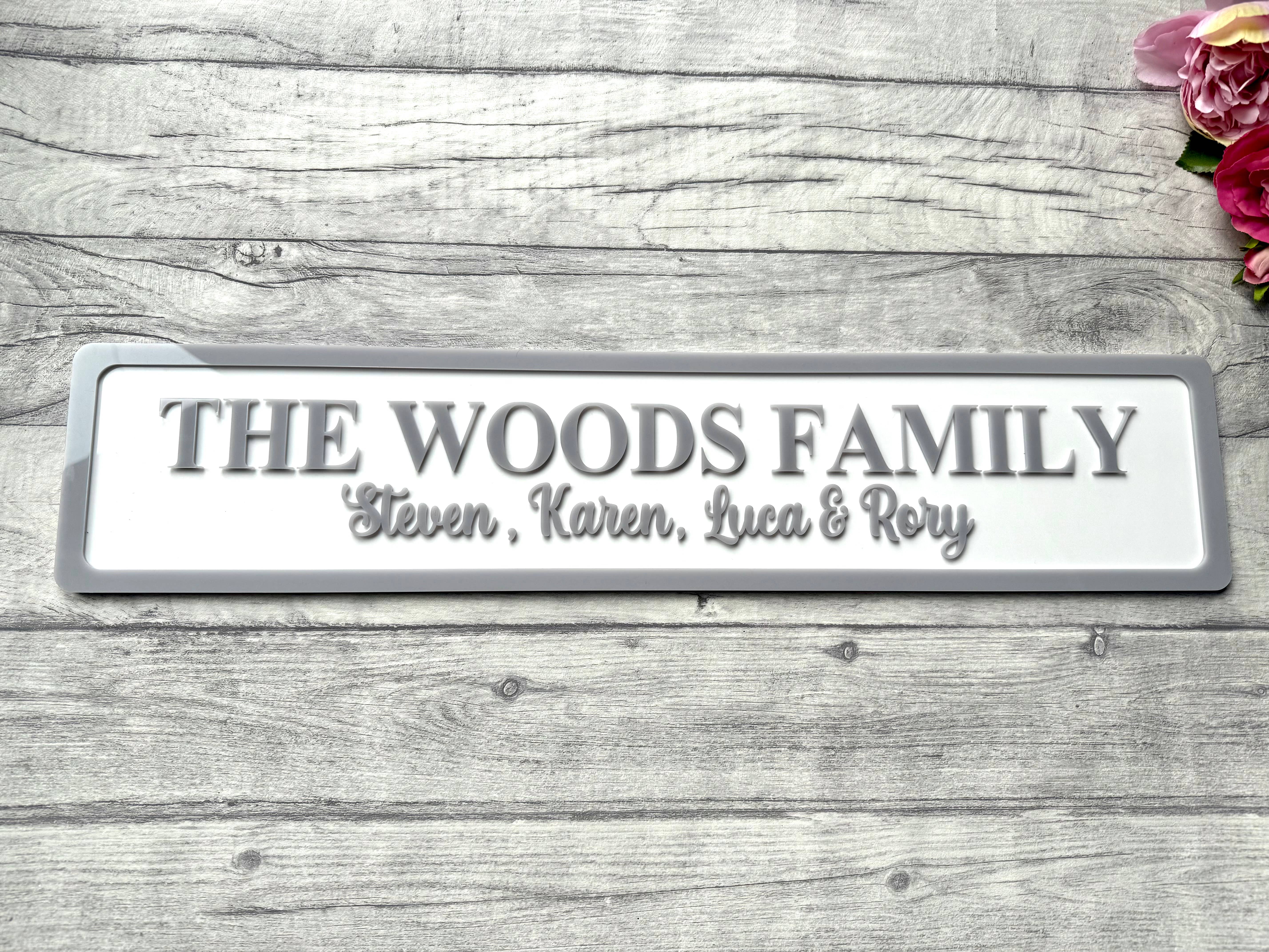Family name plaque on a wooden surface with flowers in the corner