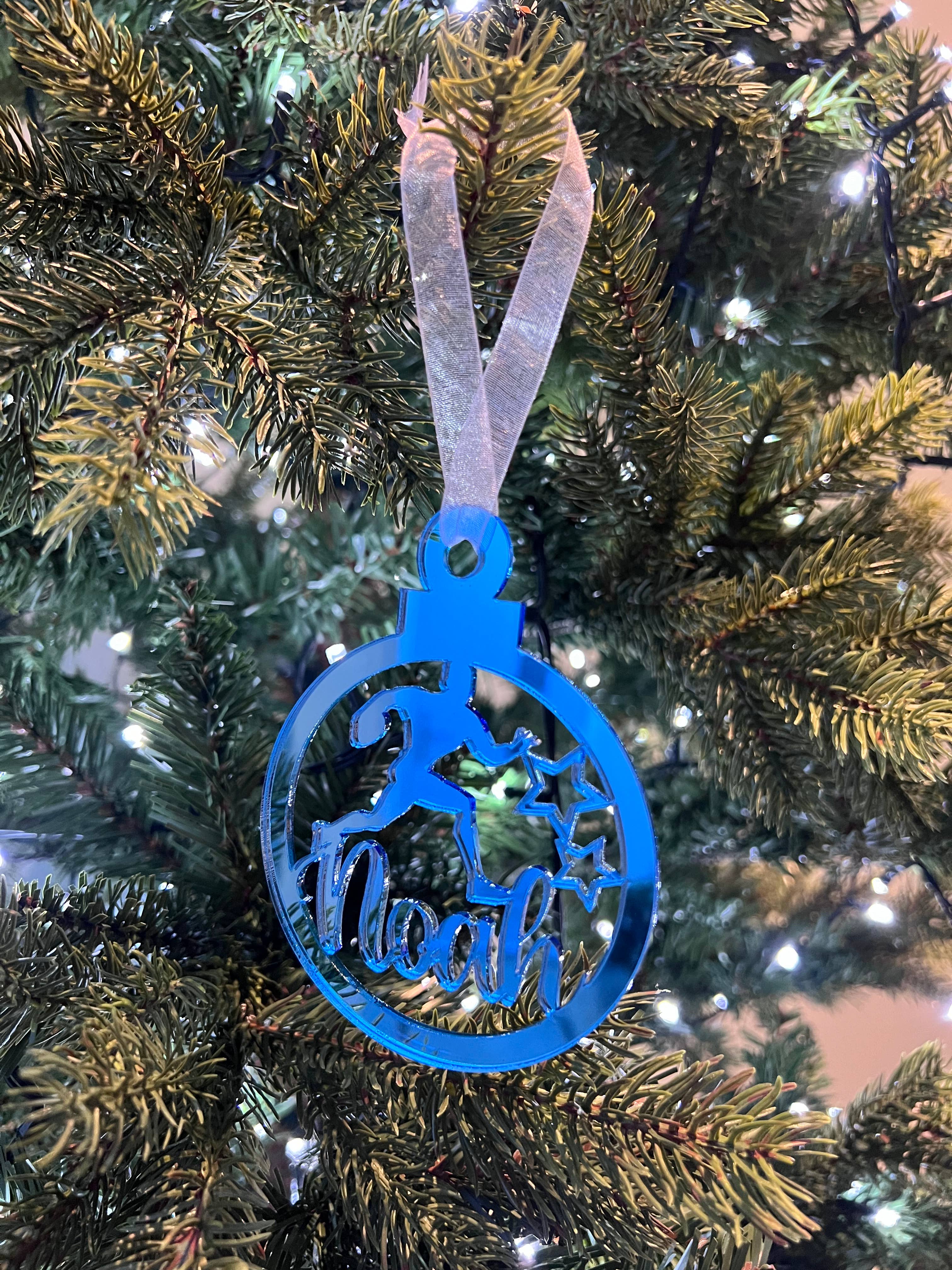 Blue acrylic Christmas ornament shaped like a fish on a tree
