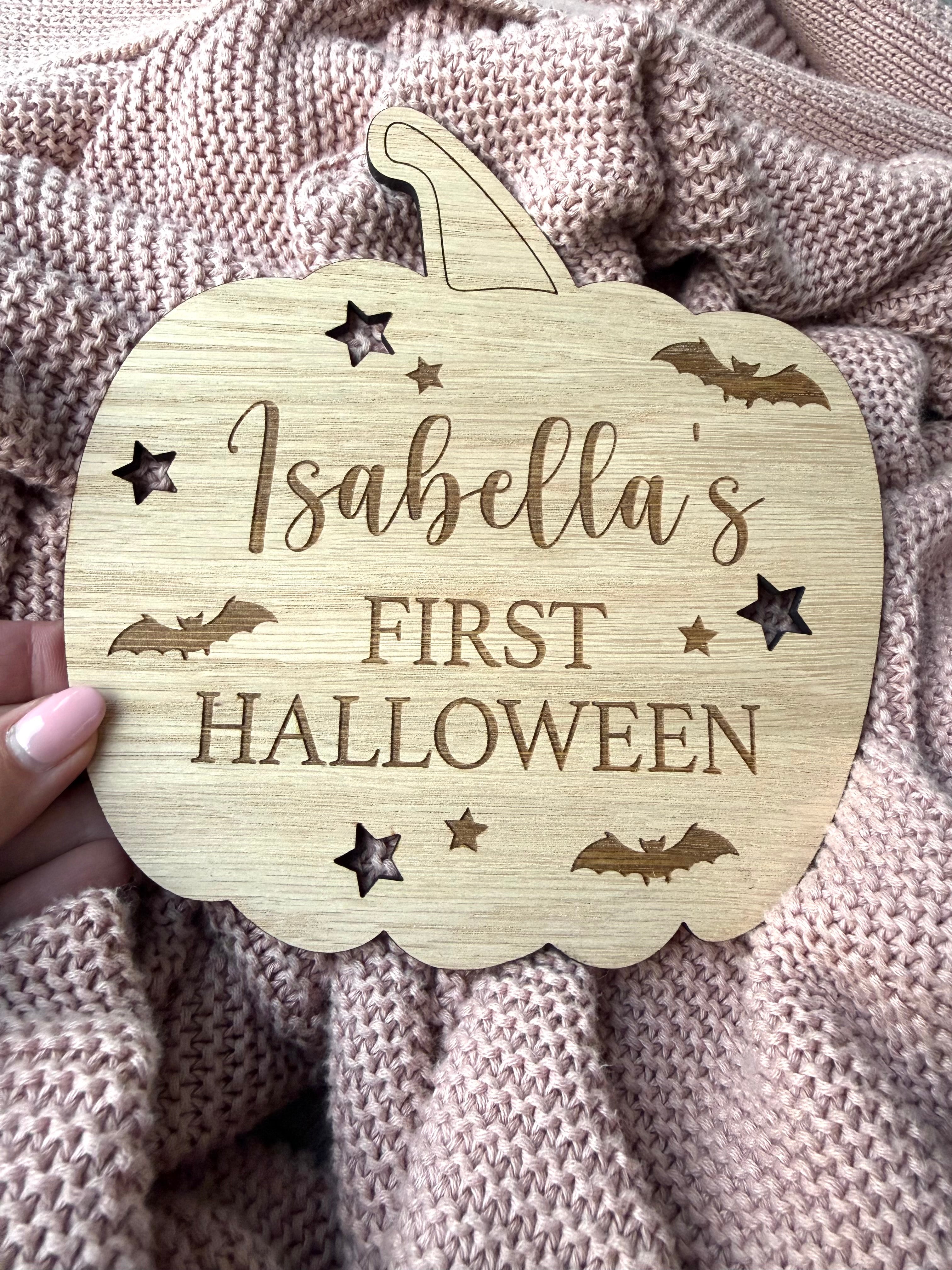 Load image into Gallery viewer, Wooden pumpkin-shaped plaque with 'Isabella's First Halloween' text on a textured fabric background
