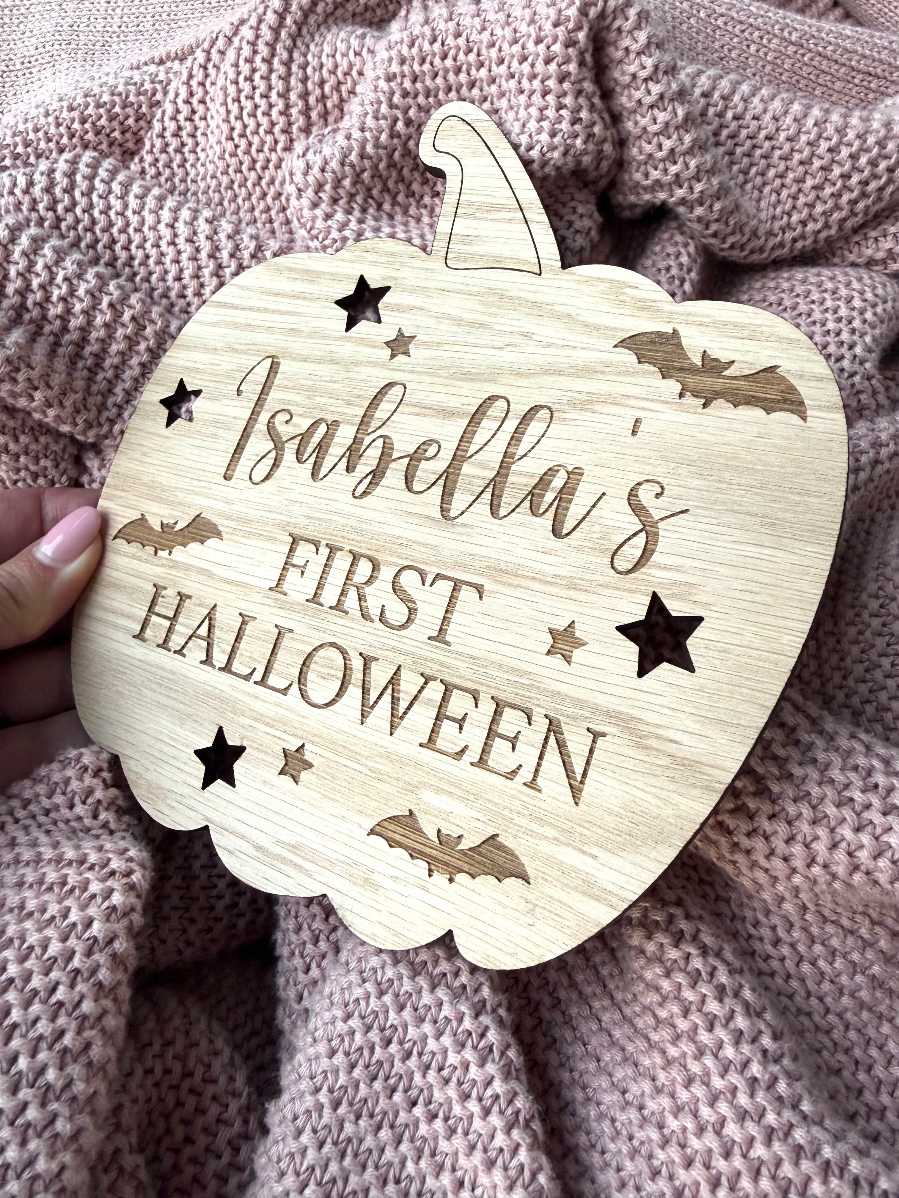 Load image into Gallery viewer, Wooden pumpkin-shaped ornament with 'Isabella's First Halloween' text on a textured fabric background
