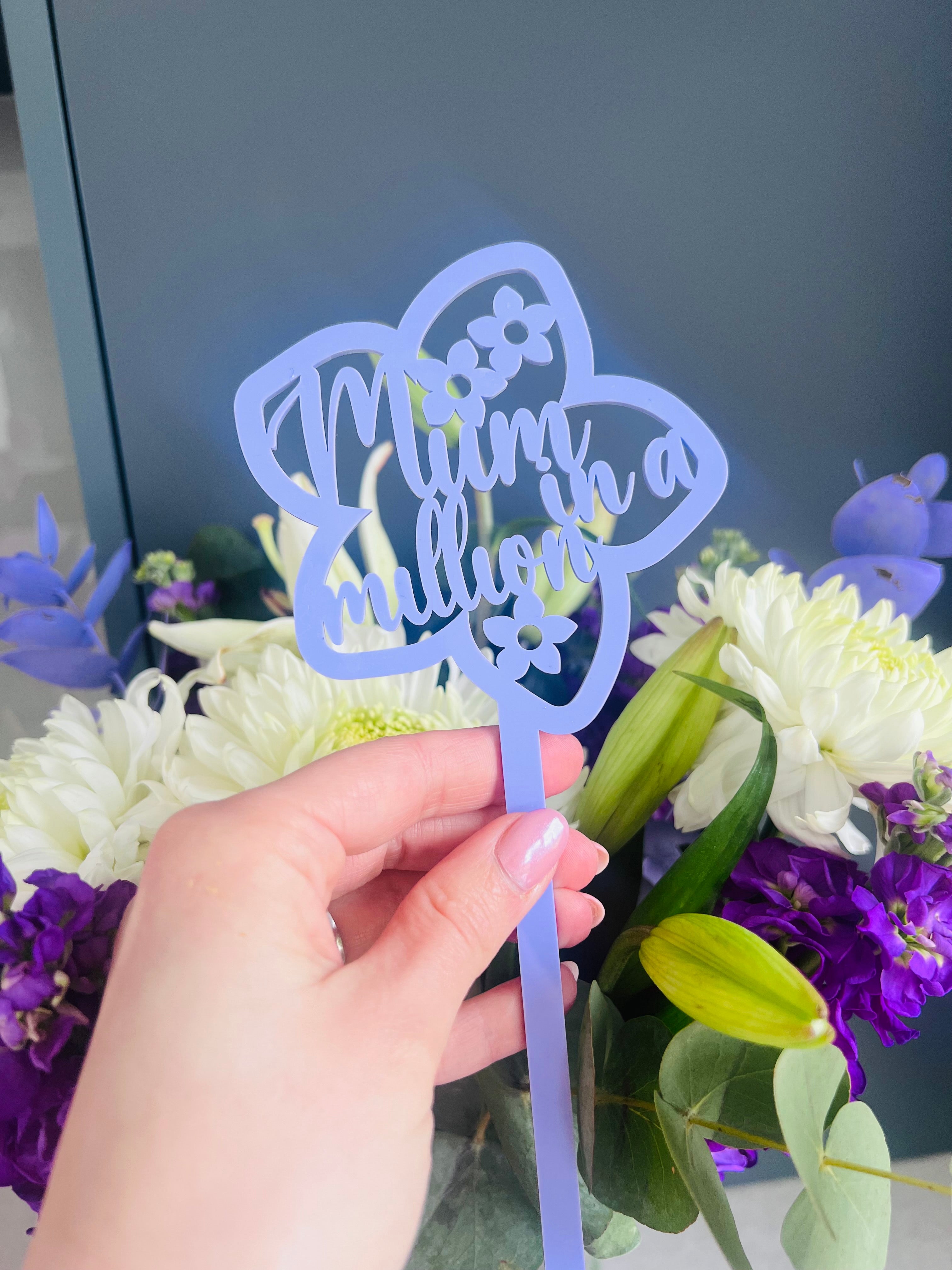 Load image into Gallery viewer, A hand holding a pink acrylic flower insert with the words 'Mum you billion' cut out of it, set against the backdrop of a bouquet of purple and white flowers.
