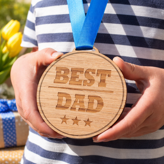 Wooden best dad medal Fathers Day gift idea from kids with ribbon and present background
