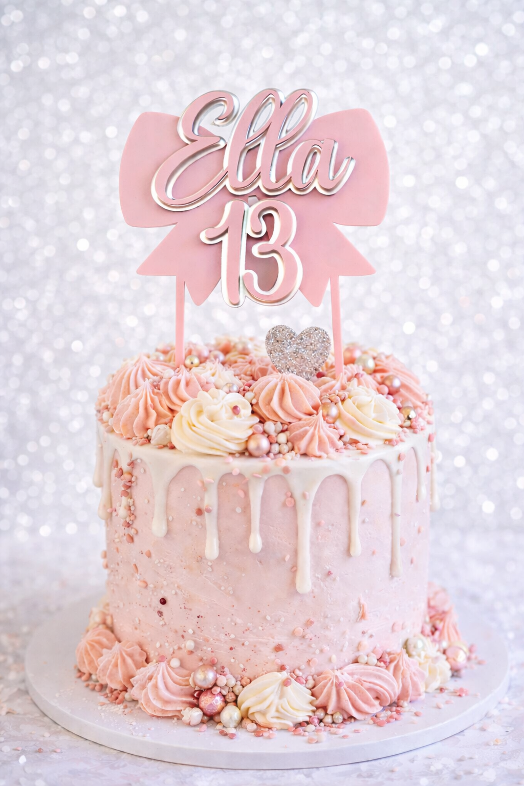 Pink birthday cake with decorative topper on a white background