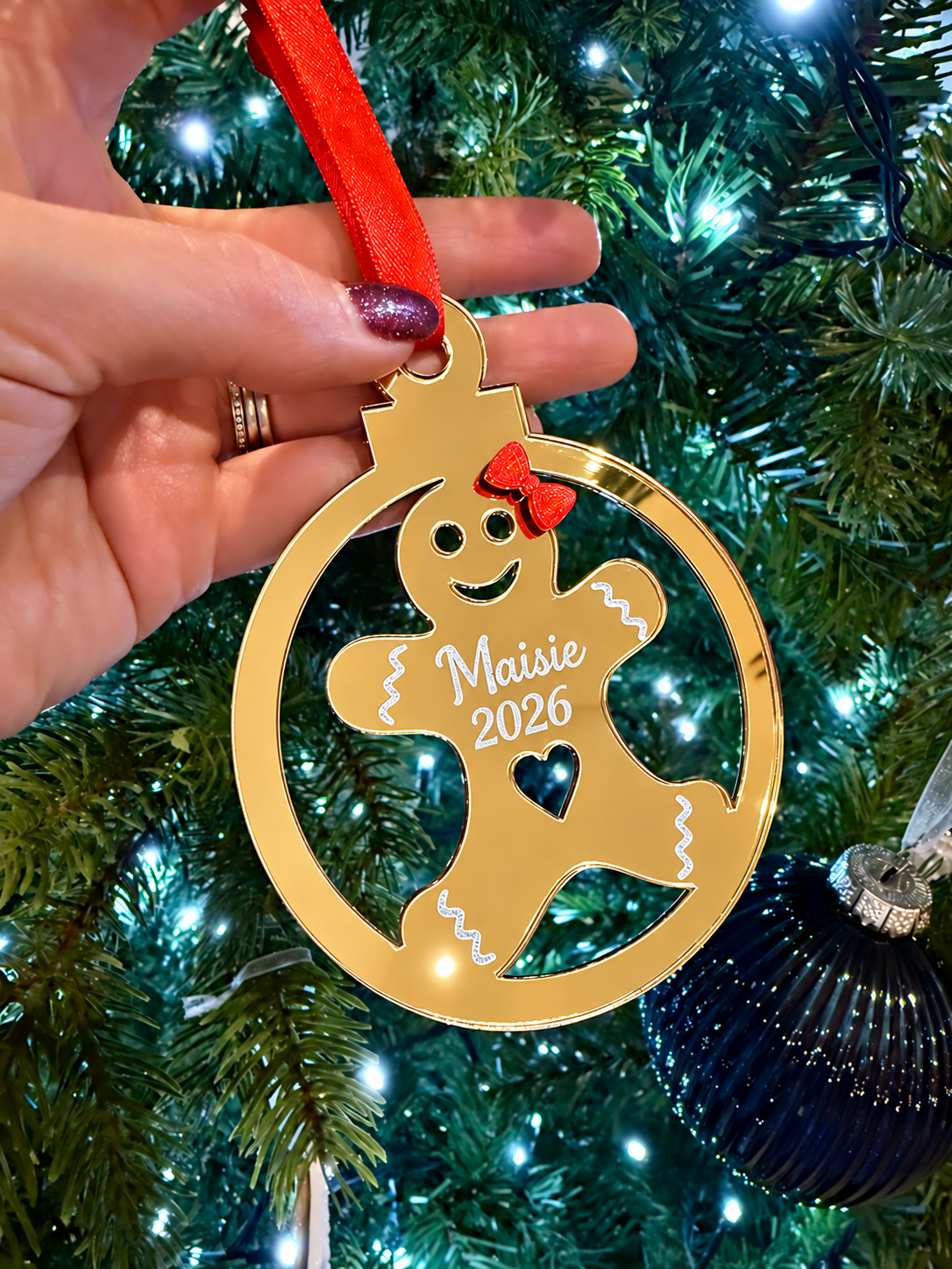 Load image into Gallery viewer, Personalised mirror gold acrylic gingerbread Christmas tree decoration engraved with Maisie 2026 and finished with a red ribbon
