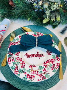 Christmas dinner table setting with personalised acrylic place name ‘Grandpa’ in red, festive plate and green napkin