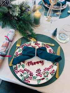 Christmas dinner table setting with personalised acrylic place name ‘Mummy’ in red, festive plate and green napkin