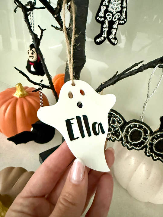 Personalised ghost Halloween tree decoration with engraved name hanging on a Halloween tree with pumpkins and spooky ornaments.