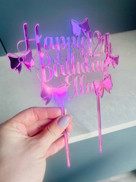 Pink mirrored acrylic personalised cake topper reading “Happy 12th Birthday Ella” displayed on a ice cream drip otake with flakes