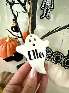 Personalised ghost Halloween tree decoration with engraved name hanging on a Halloween tree with pumpkins and spooky ornaments.