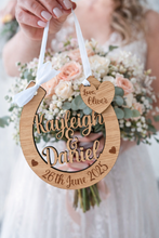 Load image into Gallery viewer, Bride holding personalised oak wooden wedding horseshoe engraved with names and date, hanging from white ribbon in front of bright colourful bridal bouquet, UK handmade wedding keepsake.

