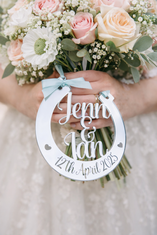 Bride holding pastel pink and cream wedding bouquet with personalised silver mirror horseshoe engraved Jenn & Ian 12th April 2025