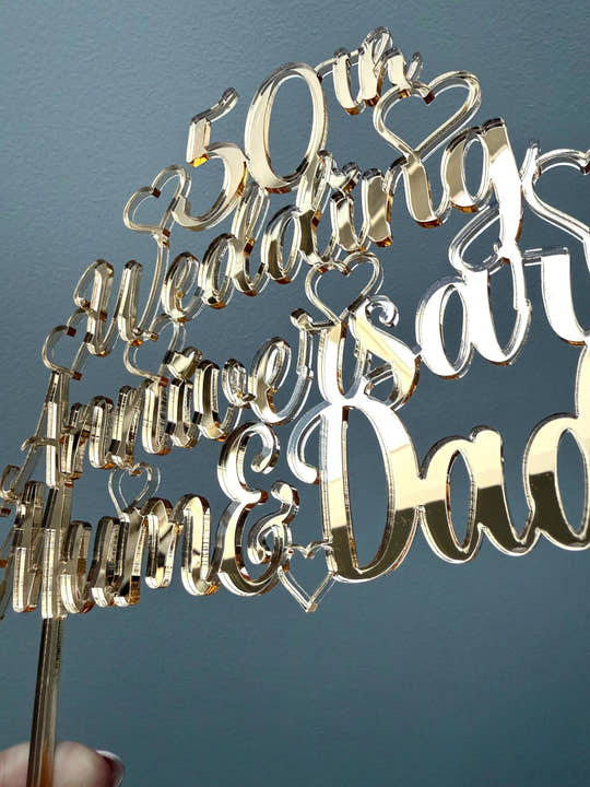 Close-up of the script lettering and hearts on the gold 50th Wedding Anniversary cake topper