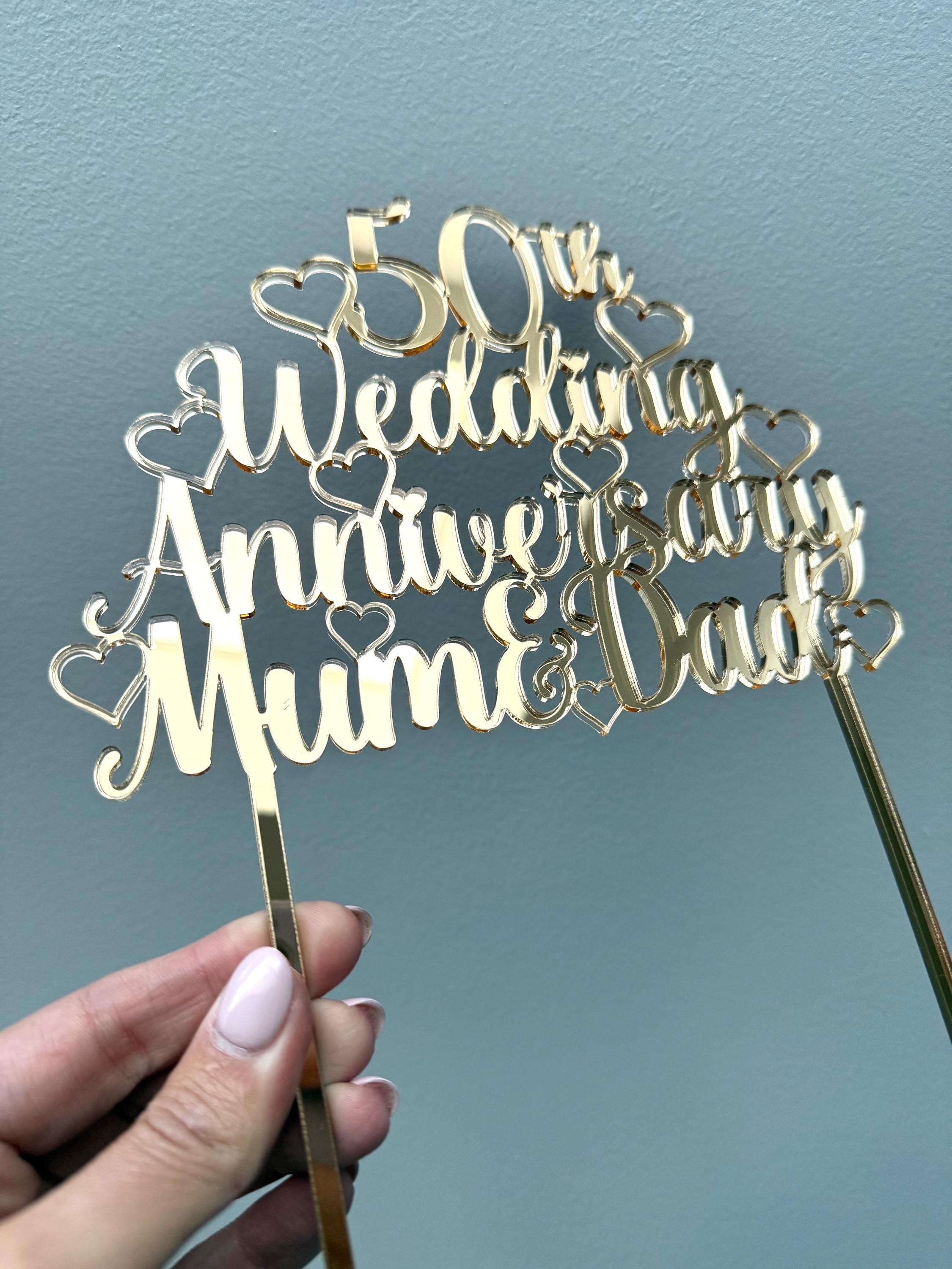 Load image into Gallery viewer, Golden wedding cake topper in gold mirror acrylic with heart details, held up to the light
