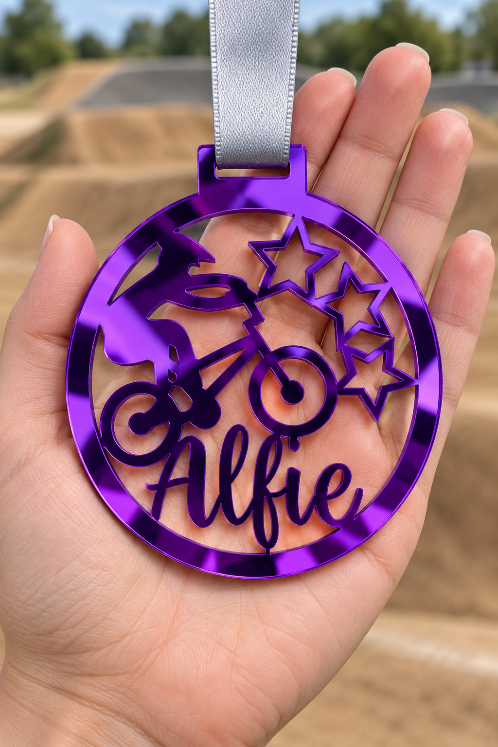 Load image into Gallery viewer, purple mirror acrylic personalised BMX medal with custom name on a silver ribbon, held in hand in front of a blurred BMX track
