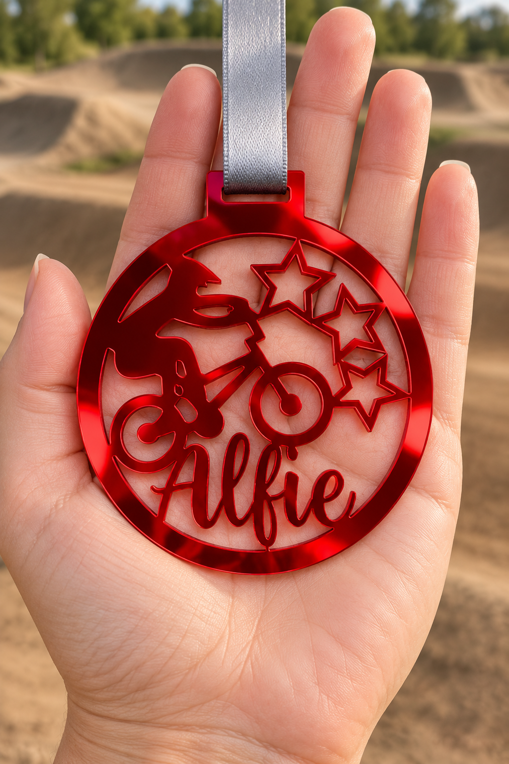 Load image into Gallery viewer, red mirror acrylic personalised BMX medal with custom name on a silver ribbon, held in hand in front of a blurred BMX track
