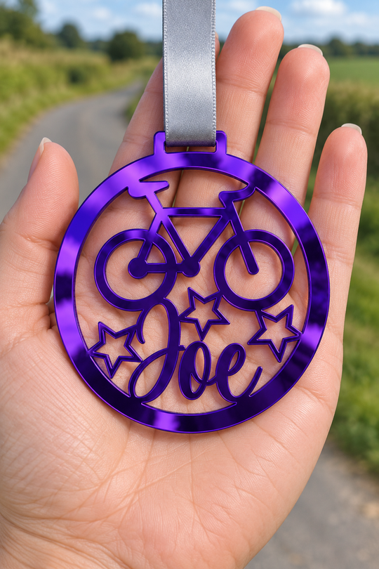 purple mirror acrylic personalised cycling medal with custom name on a silver ribbon, held in hand in front of a blurred country road