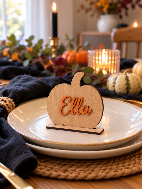 Personalised oak pumpkin place name with the name Ella in orange, standing in an oak stand on a dinner plate