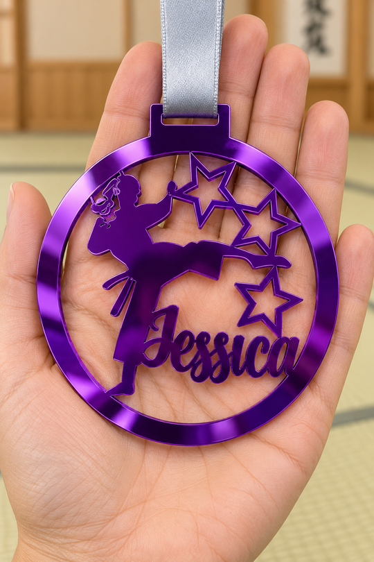 purple mirror acrylic personalised karate girl medal with custom name on a silver ribbon, held in hand in front of a blurred dojo