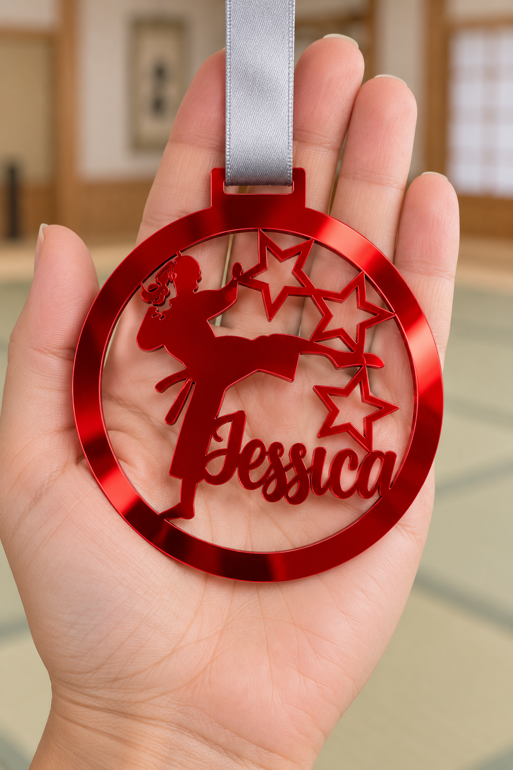 Load image into Gallery viewer, red mirror acrylic personalised karate girl medal with custom name on a silver ribbon, held in hand in front of a blurred dojo
