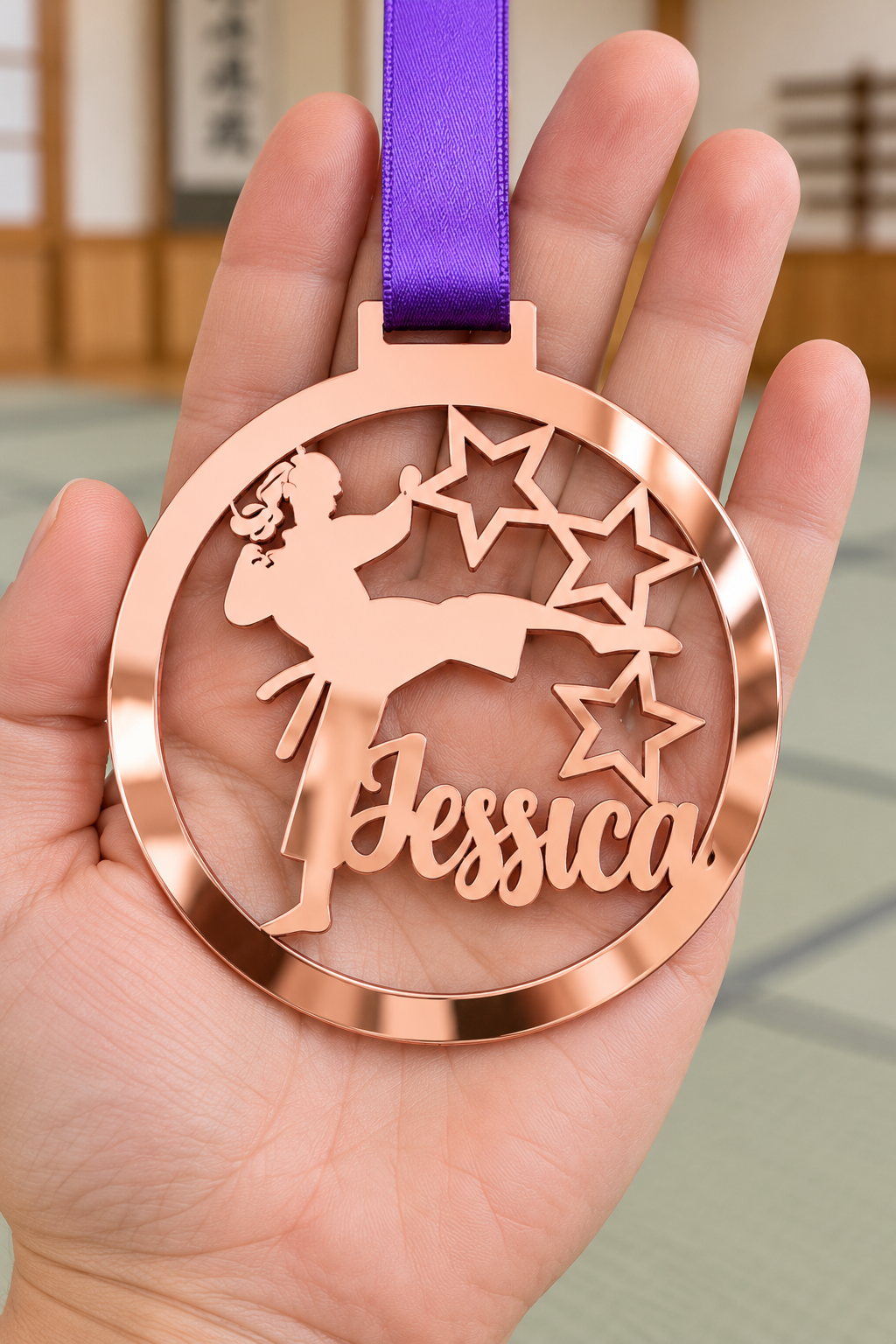 Load image into Gallery viewer, rose gold mirror acrylic personalised karate girl medal with custom name on a purple ribbon, held in hand in front of a blurred dojo
