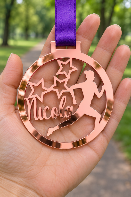 rose gold mirror acrylic personalised running medal with custom name on a purple ribbon, held in hand in front of a blurred park running path