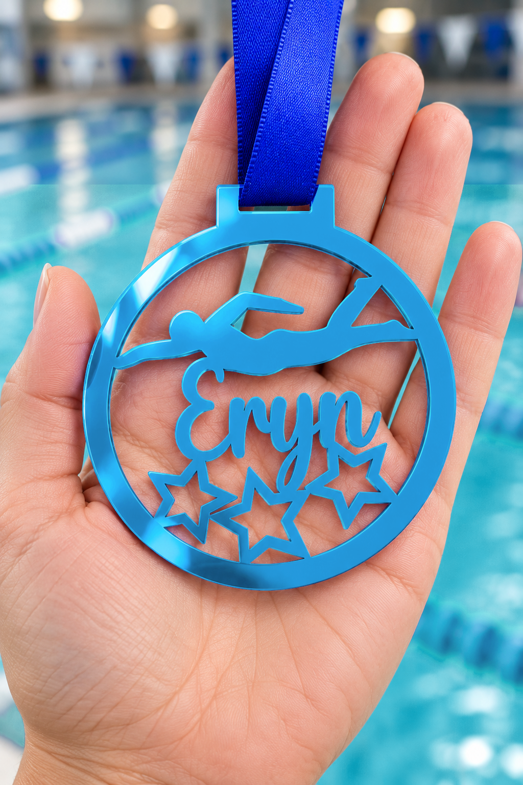 Load image into Gallery viewer, blue mirror acrylic personalised swimming medal with custom name on a blue ribbon, held in hand in front of a blurred swimming pool
