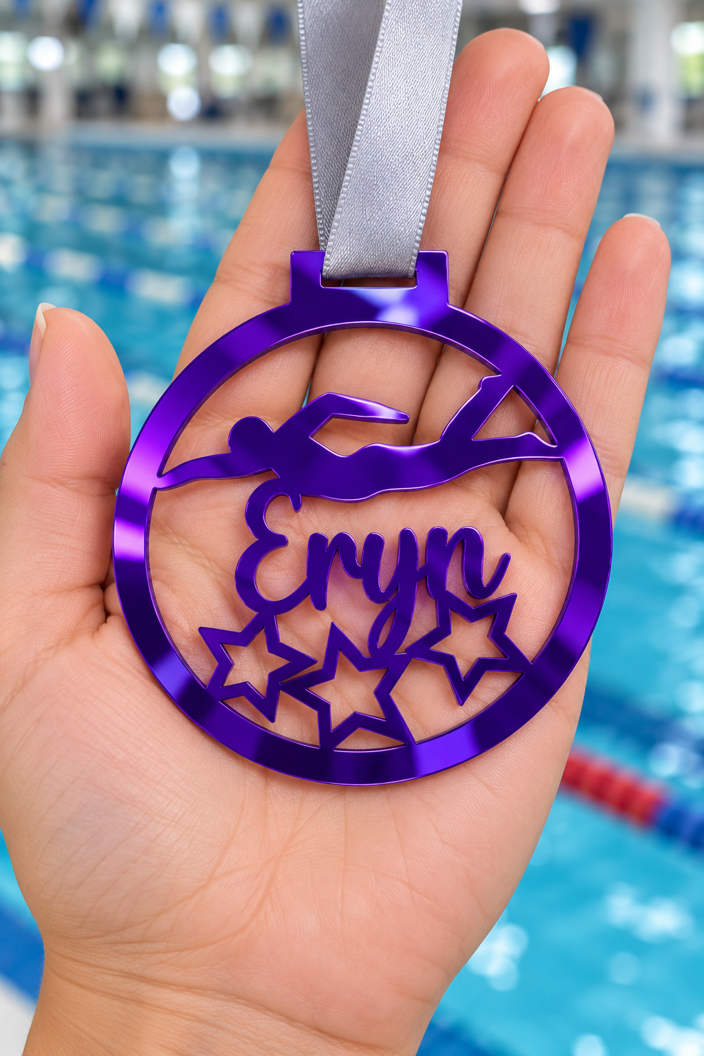 Load image into Gallery viewer, purple mirror acrylic personalised swimming medal with custom name on a silver ribbon, held in hand in front of a blurred swimming pool

