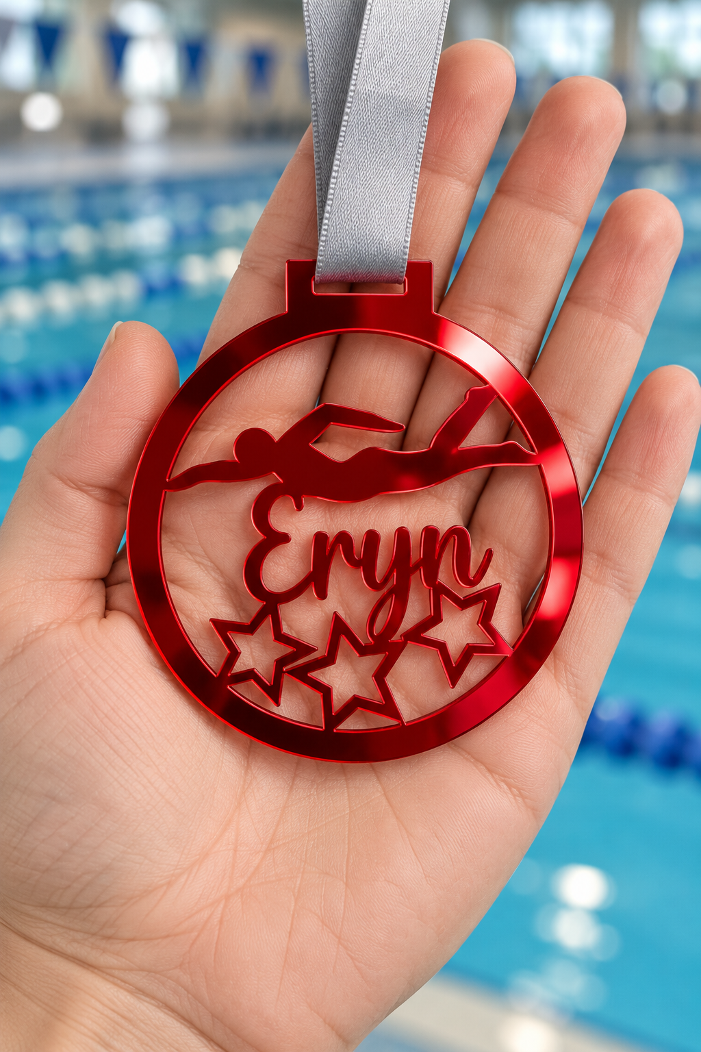 Load image into Gallery viewer, red mirror acrylic personalised swimming medal with custom name on a silver ribbon, held in hand in front of a blurred swimming pool
