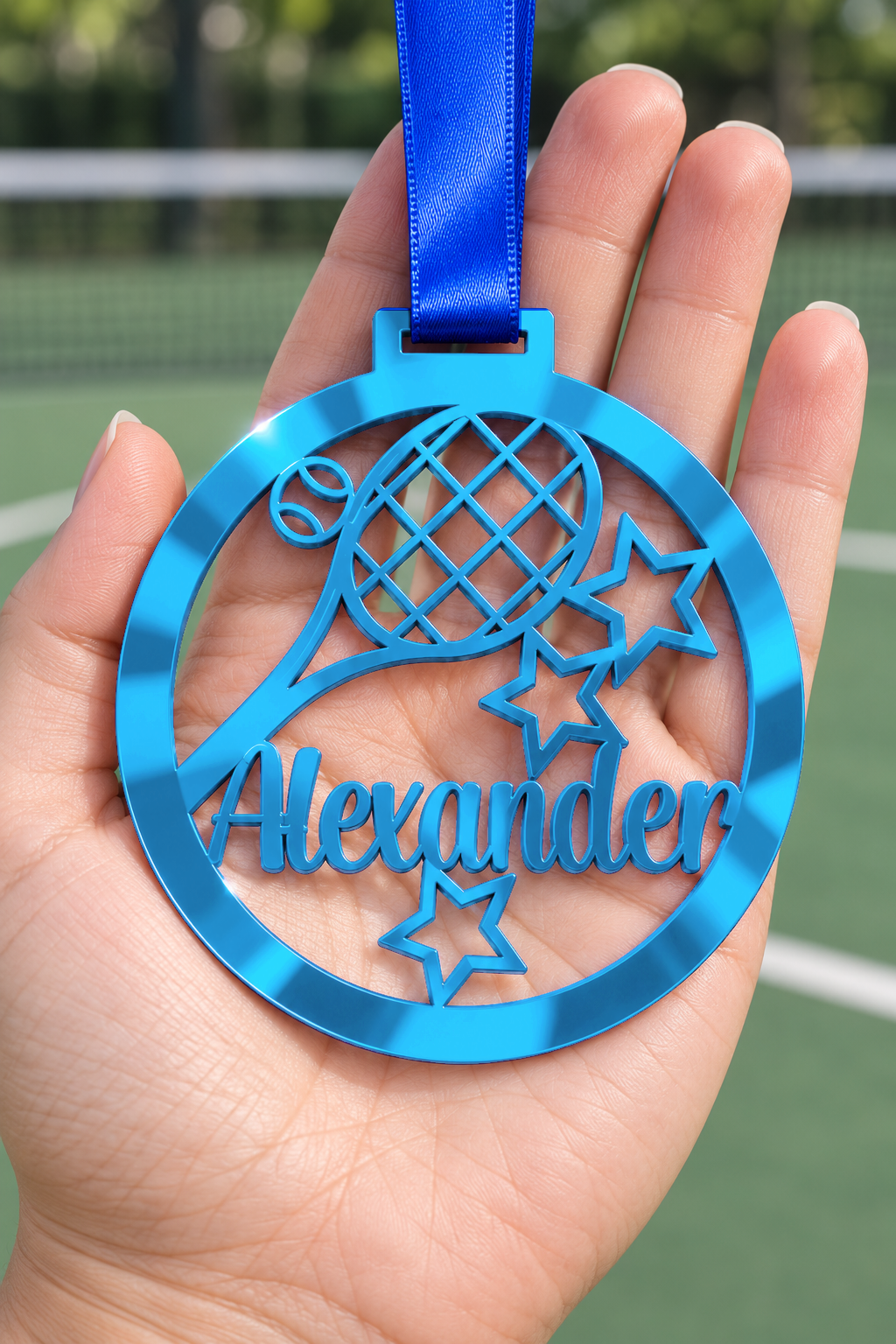 Load image into Gallery viewer, blue mirror acrylic personalised tennis medal with custom name on a blue ribbon, held in hand in front of a blurred tennis court
