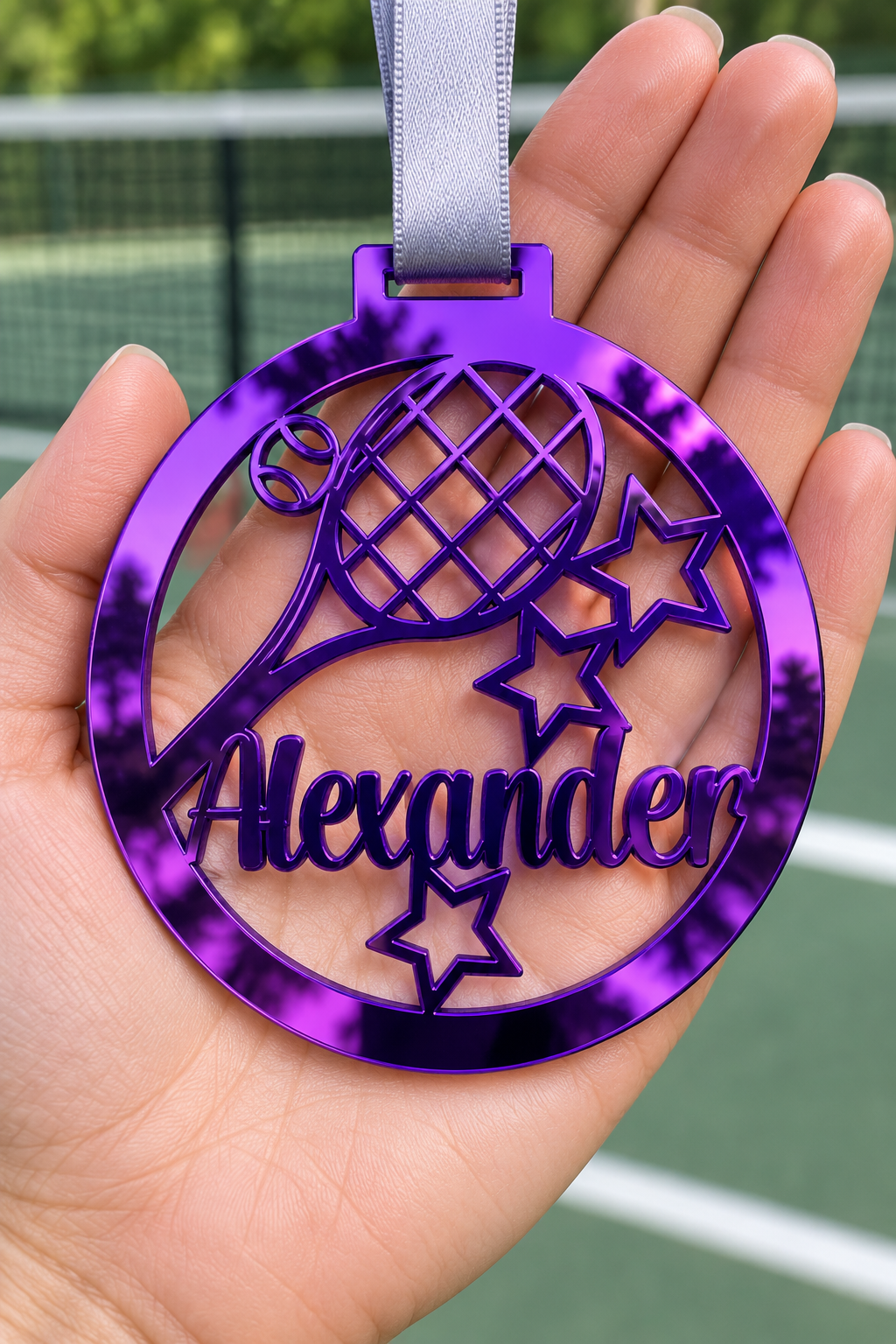 Load image into Gallery viewer, purple mirror acrylic personalised tennis medal with custom name on a silver ribbon, held in hand in front of a blurred tennis court
