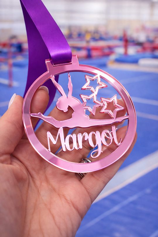 pale pink mirror acrylic personalised gymnastics medal held in hand with custom name design